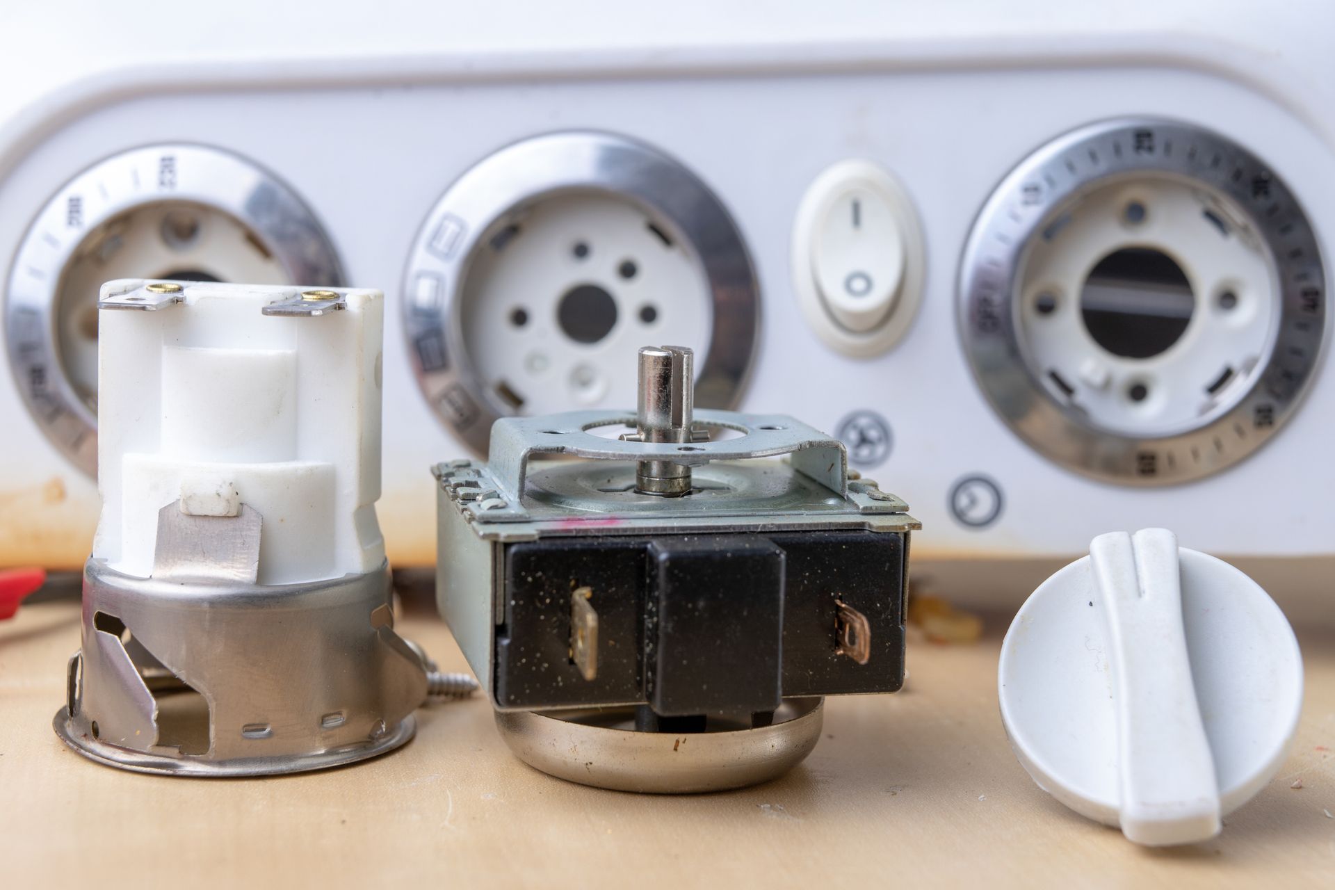 Close-up of disassembled oven controls, including dials, switches, and interior components.