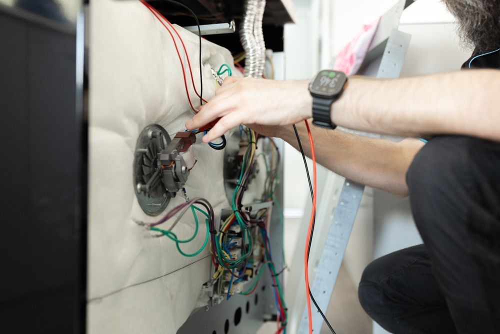 Regional Appliance & Electrical Services technician inspecting wiring inside an appliance.