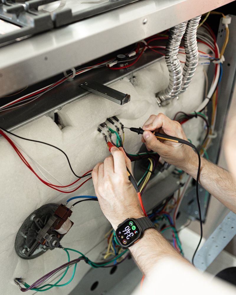 Regional Appliance & Electrical Services technician testing appliance wiring with a multimeter.