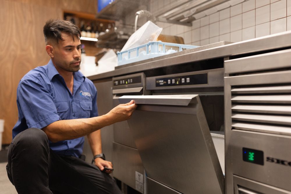Regional Appliance & Electrical Services technician servicing a commercial dishwasher.