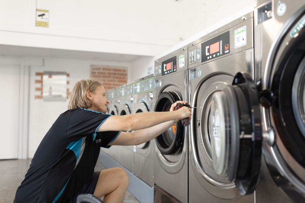 Regional Appliance & Electrical Services technician repairing a commercial washer