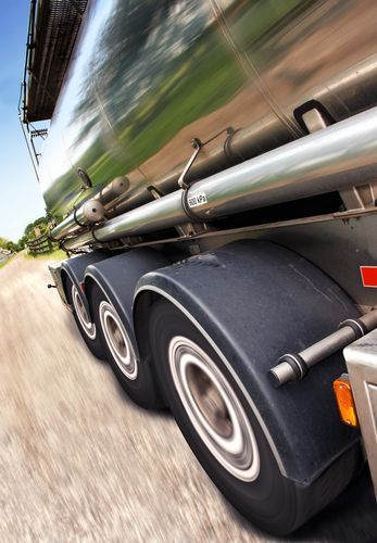 Truck wheels on a road, blurred background of sky and fields, motion.