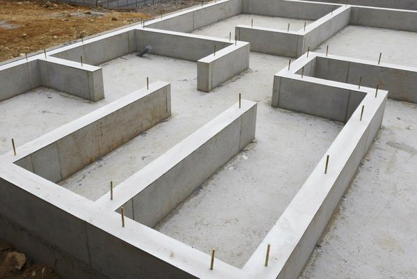 Concrete foundation framework on a construction site. Gray rectangular forms, ground level.