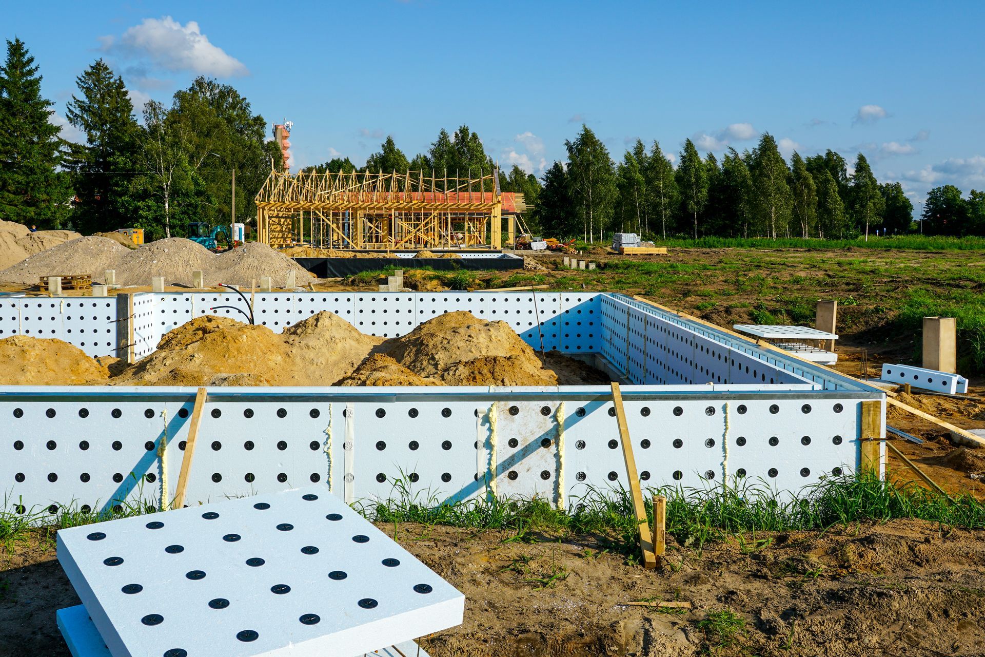Icf concrete wall forms being put up next to the building of a house in the country.