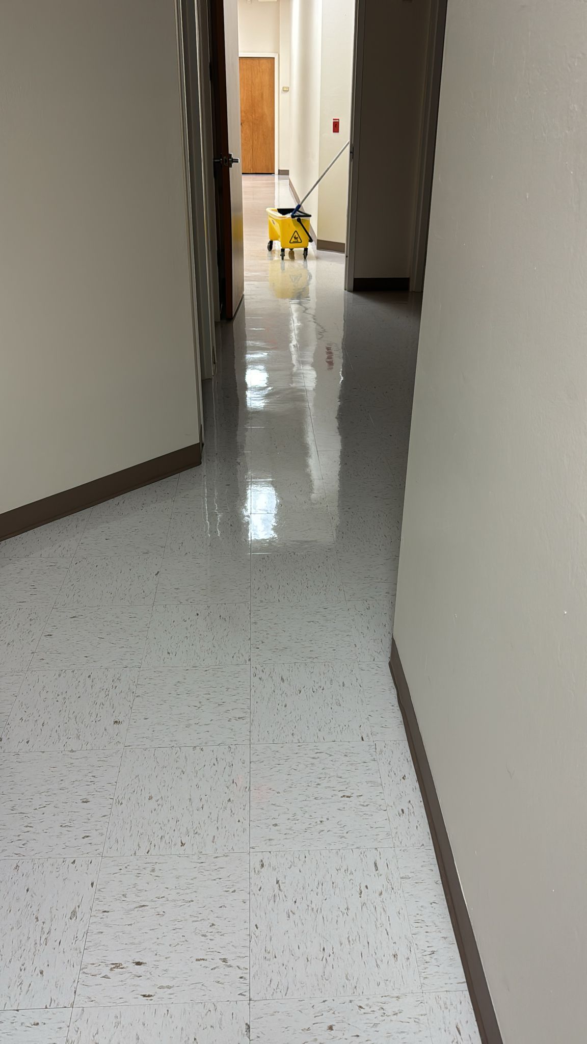 A hallway with a yellow mop on the floor