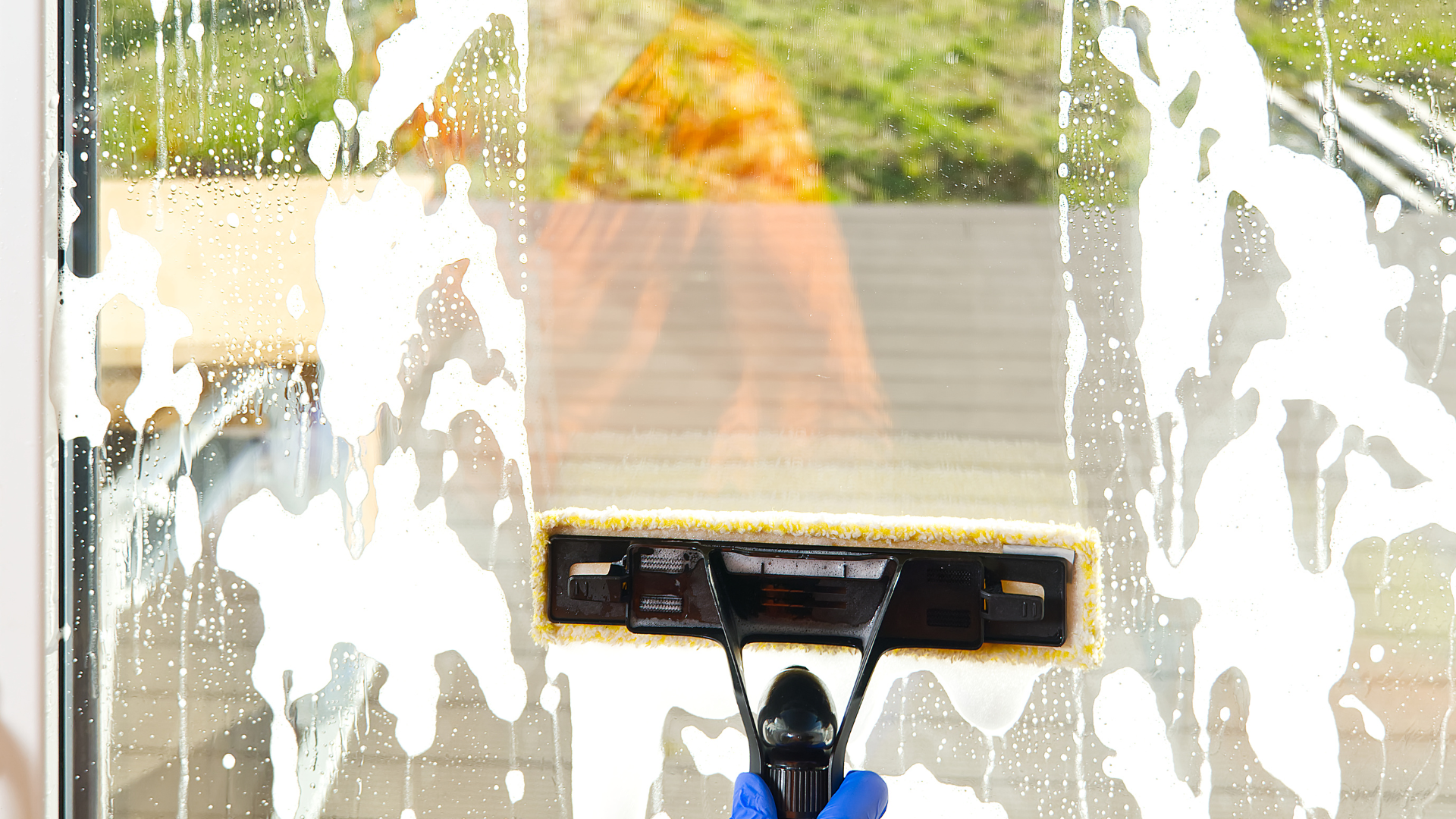 A person is cleaning a window with a mop.