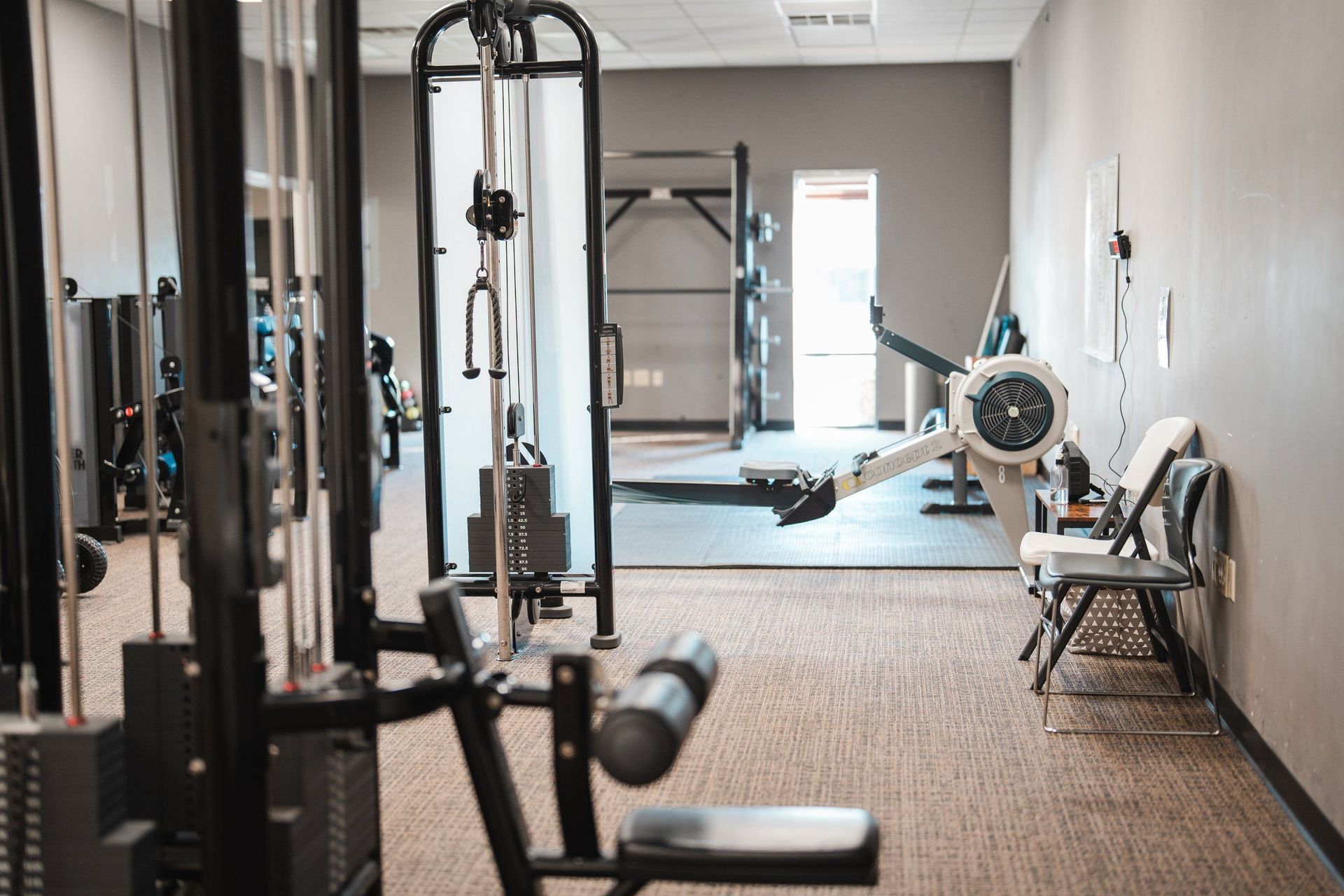 A gym filled with lots of exercise equipment and a chair.