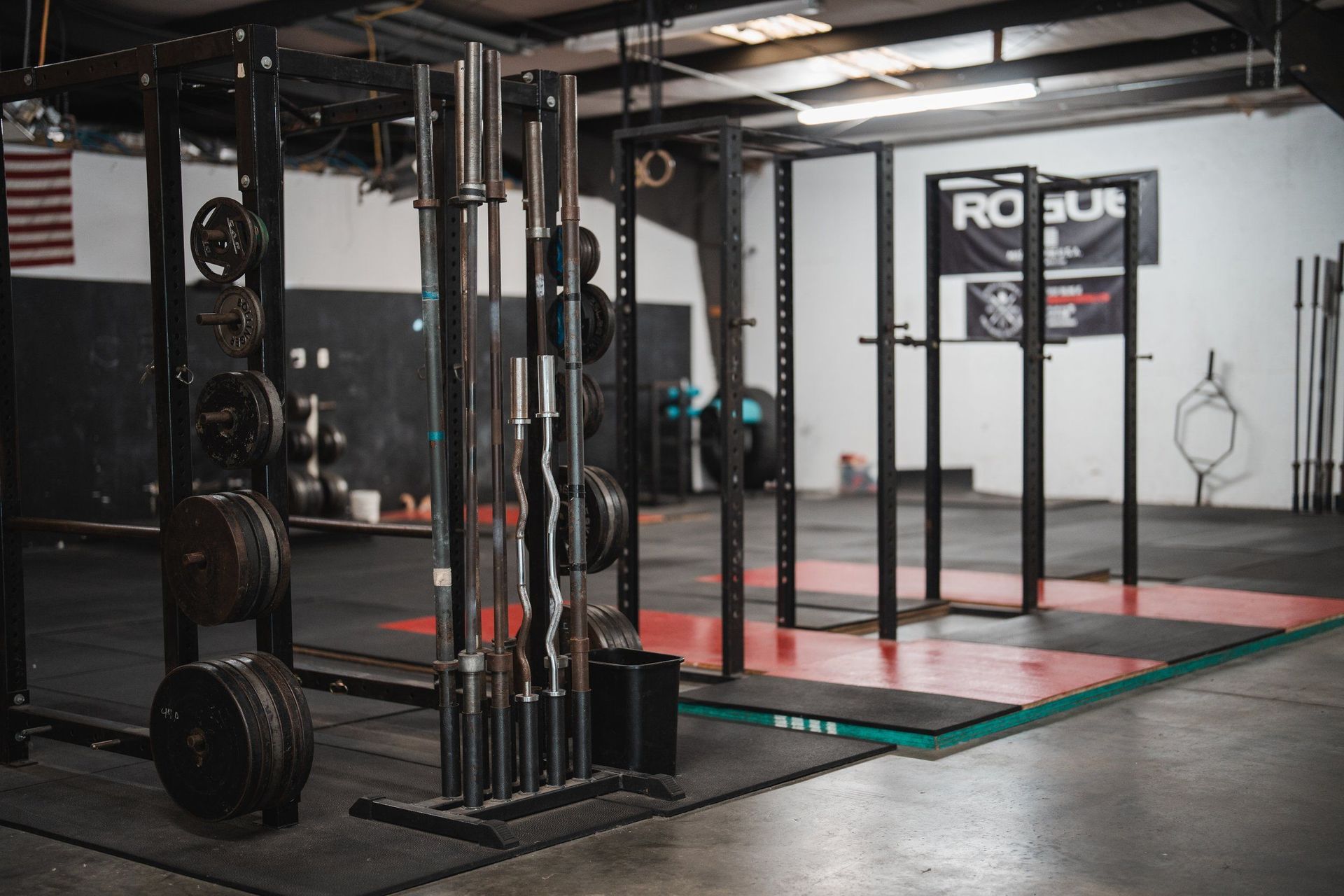 A gym with a lot of weights and bars on the floor.