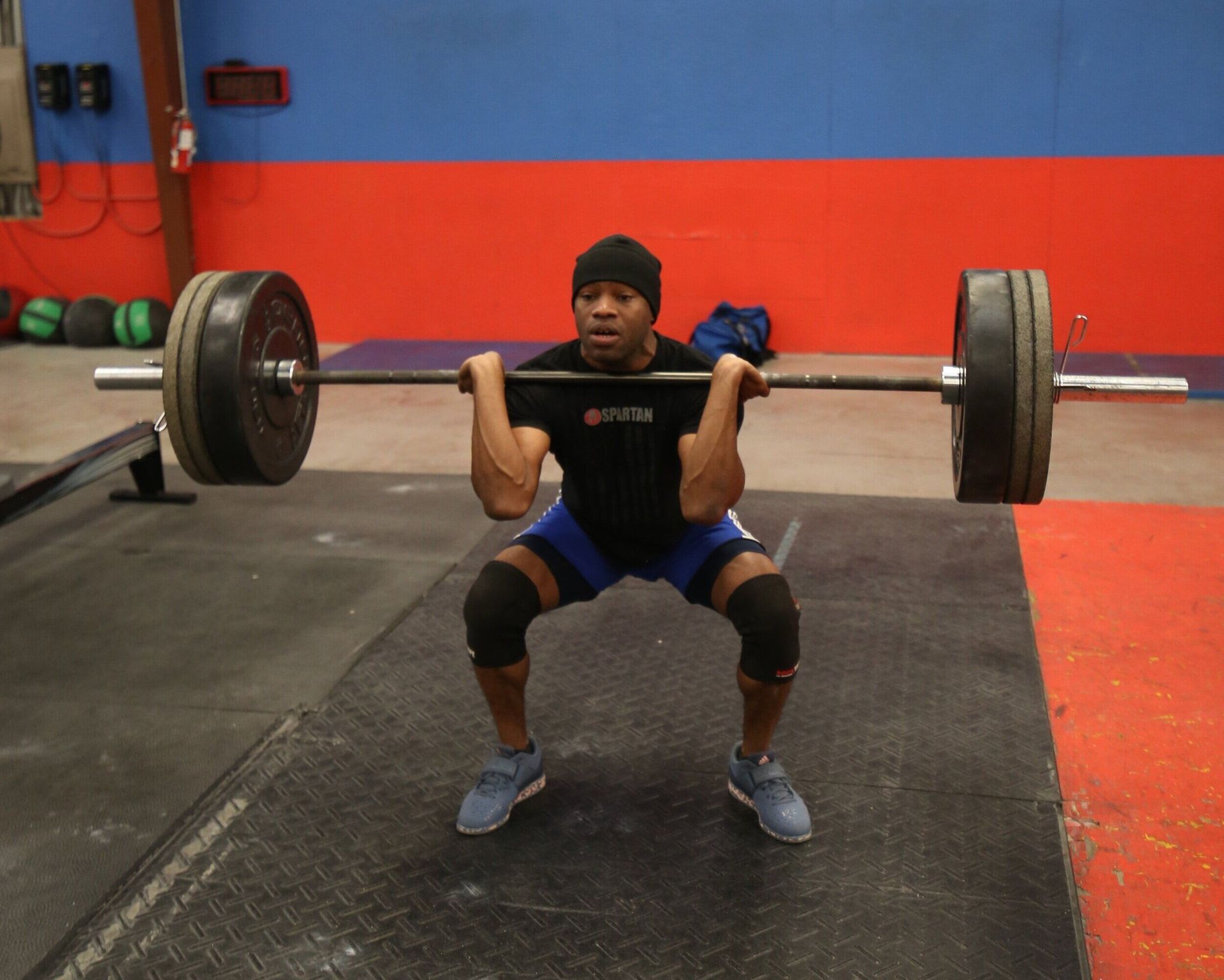 A man squatting with a barbell in a gym