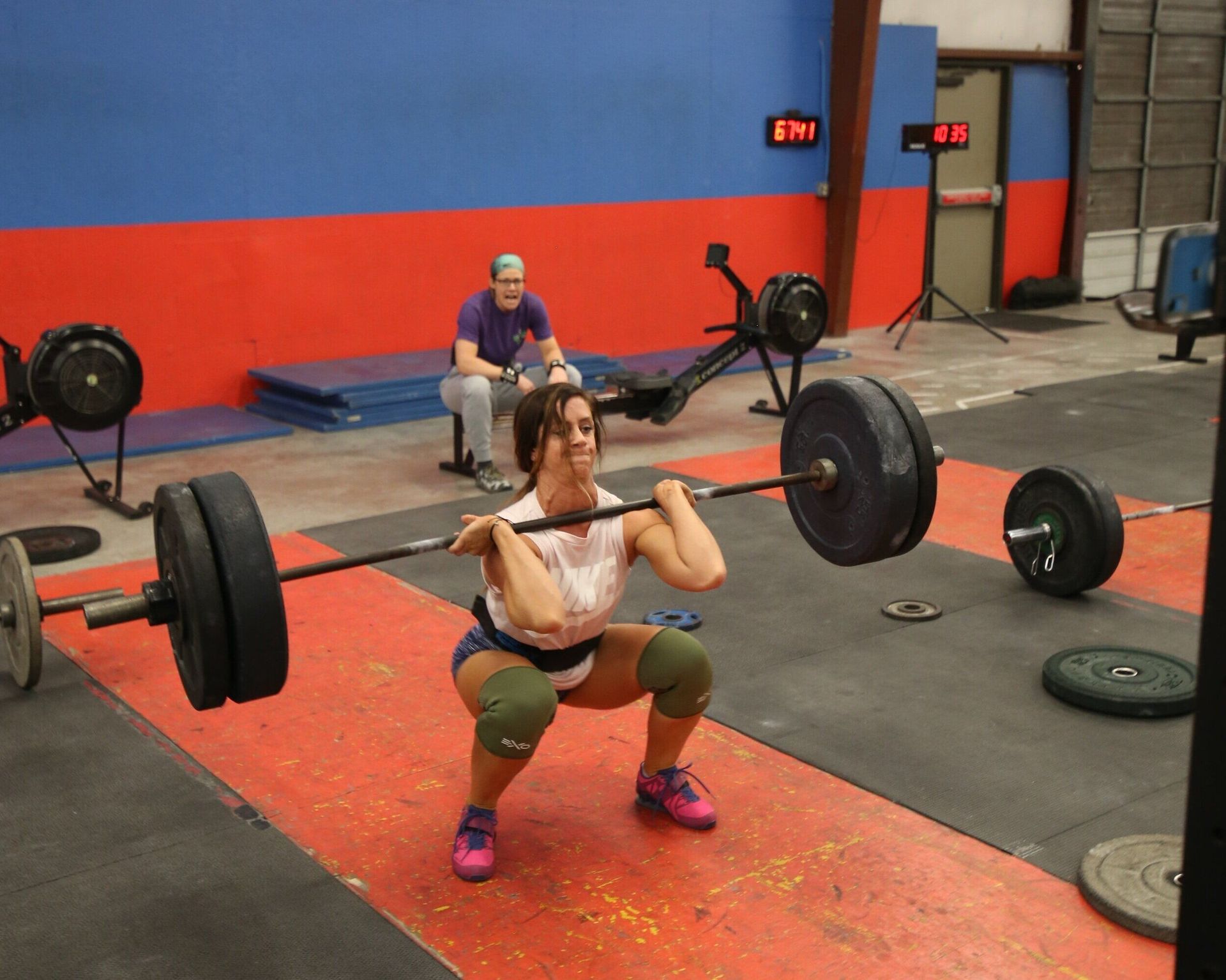 A woman squatting with a barbell in a gym