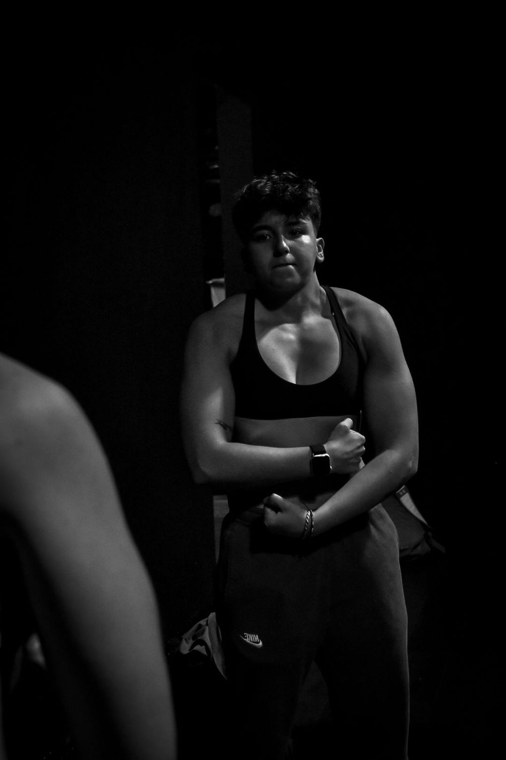 A black and white photo of a woman standing in front of a mirror.