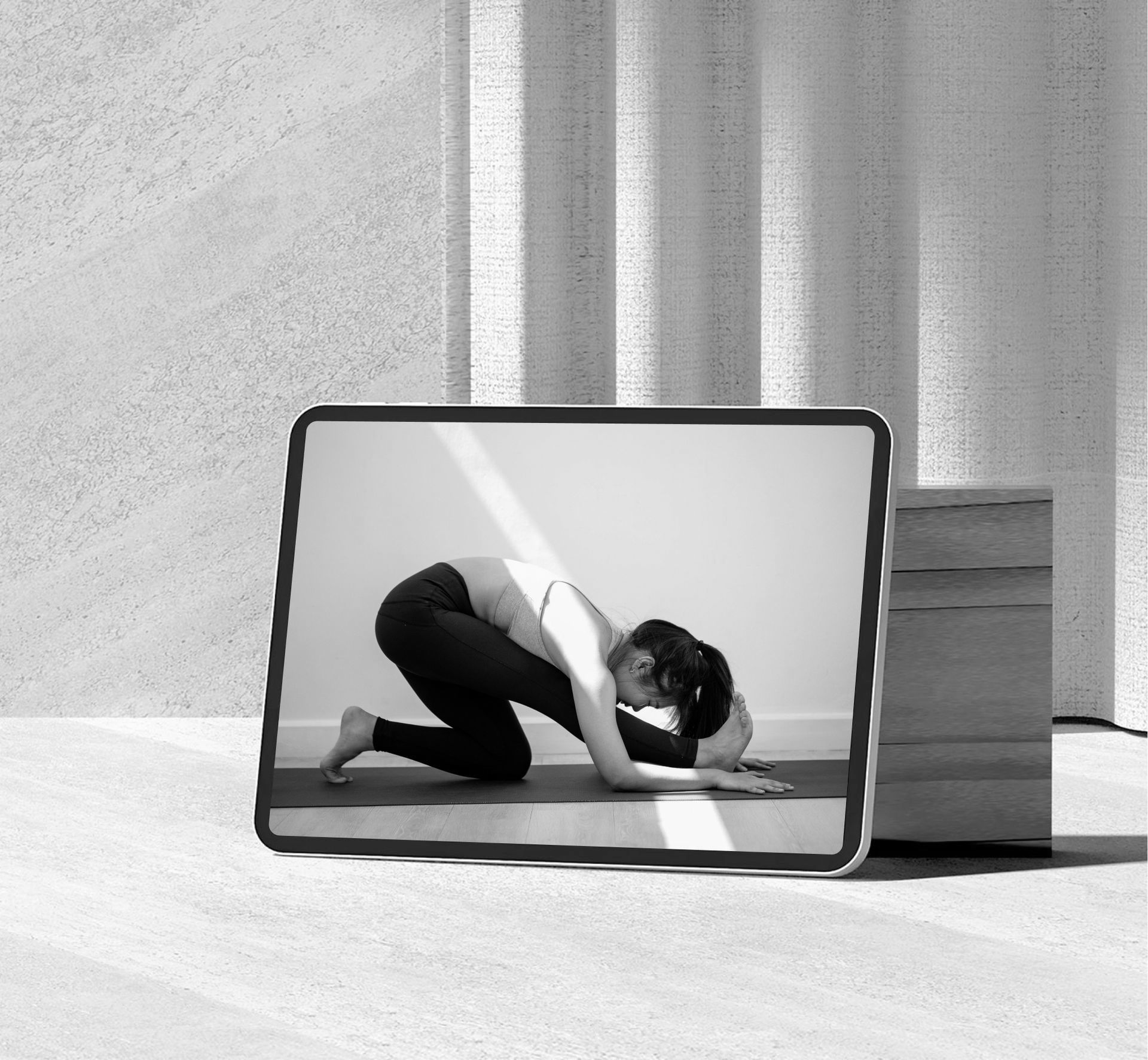 A black and white photo of a woman doing yoga on a tablet