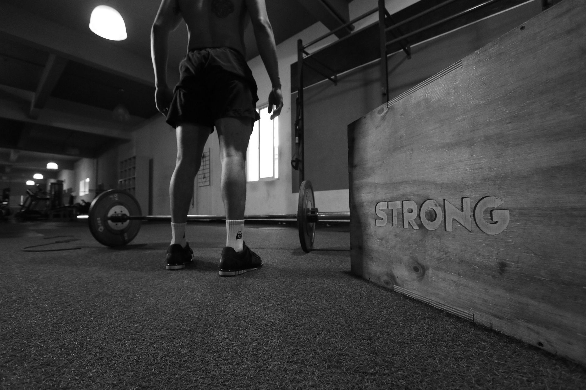 A black and white photo of a man lifting a barbell in a gym