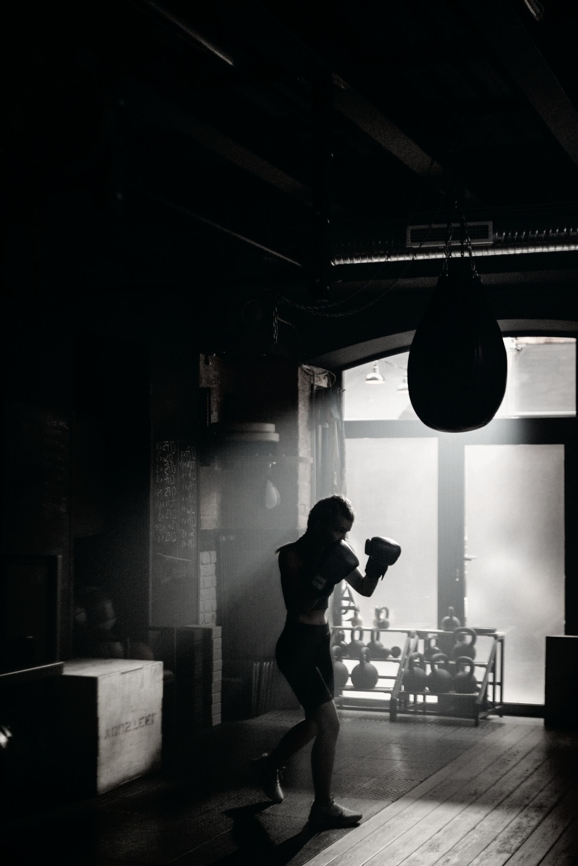 A black and white photo of a person boxing in a gym.