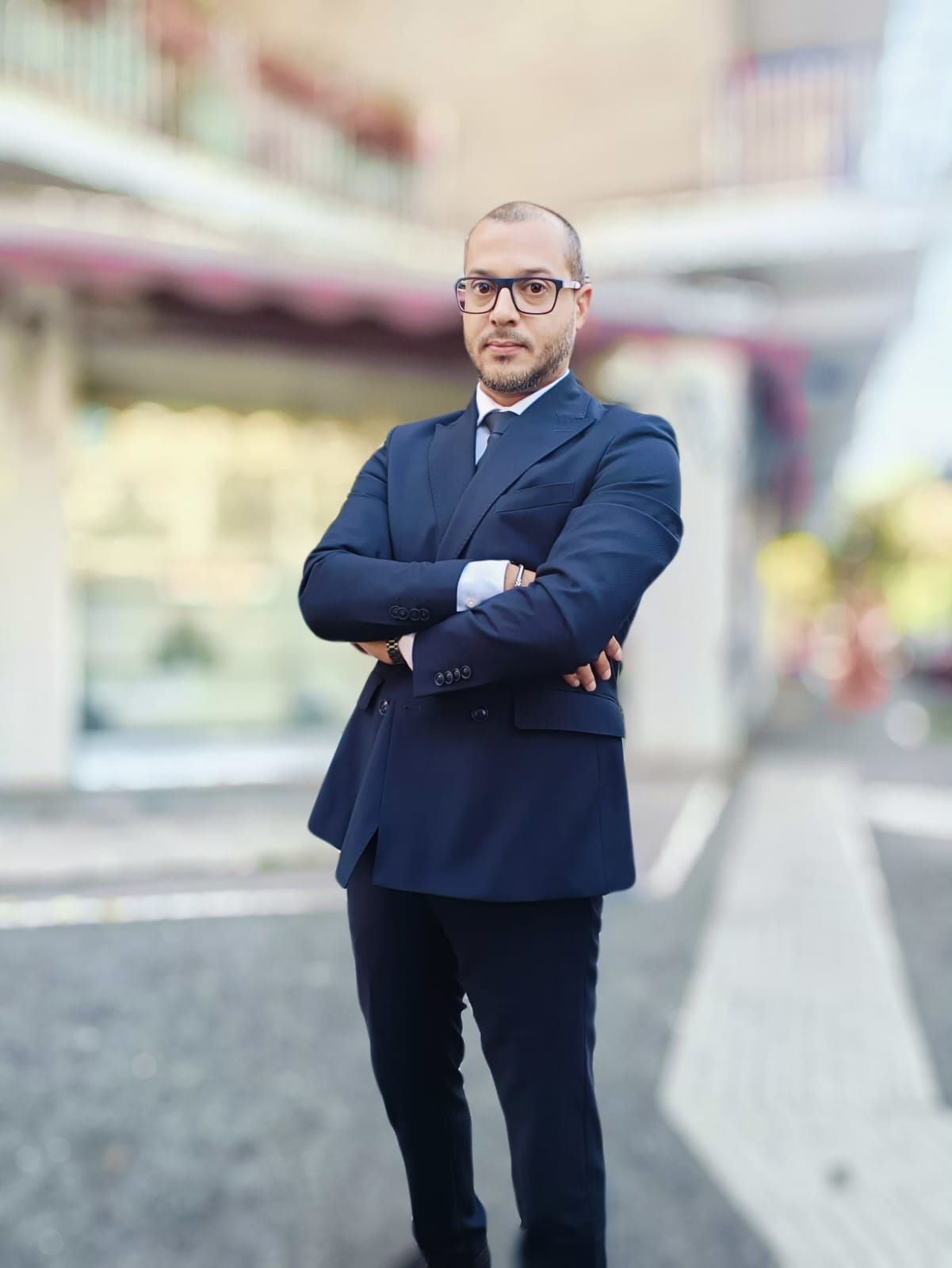 A man in a suit and tie is standing with his arms crossed.
