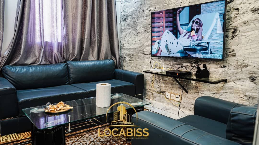 Un salon avec un canapé, une chaise, une table et une télévision.