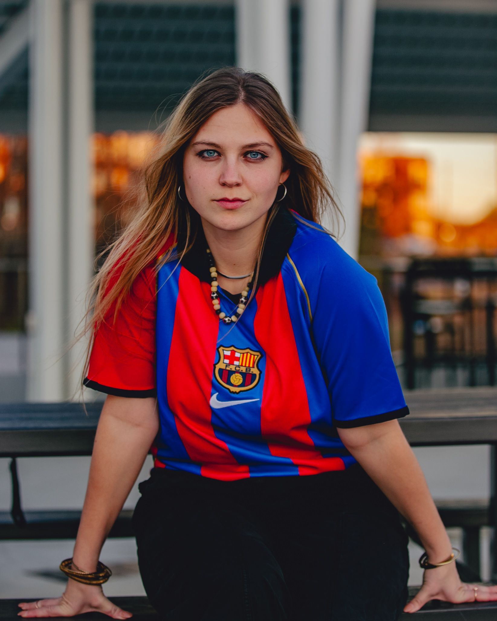 Woman wearing a red and blue Barcelona jersey, sitting at a table outdoors.