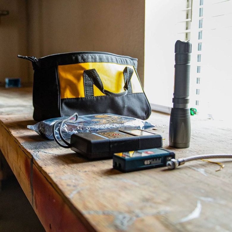 A black and yellow bag is sitting on a wooden table next to a flashlight.