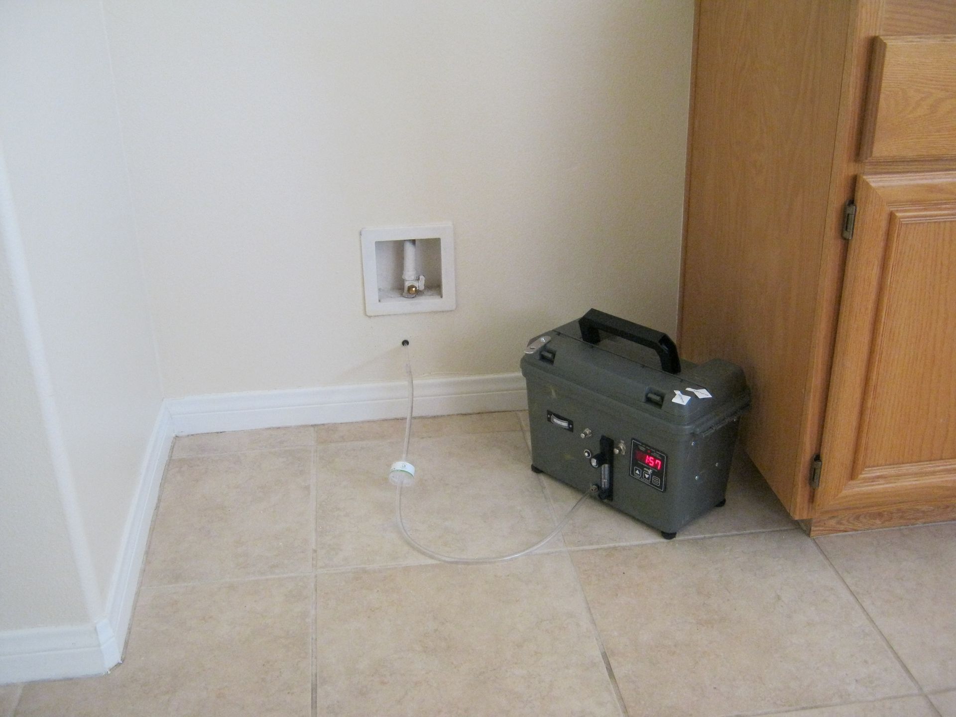 A box is sitting on the floor next to a wooden cabinet.