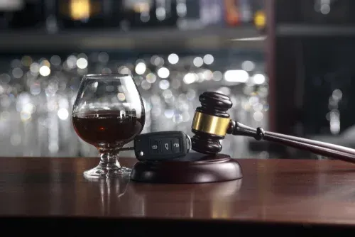 A glass of cognac and a judge 's gavel on a bar counter.