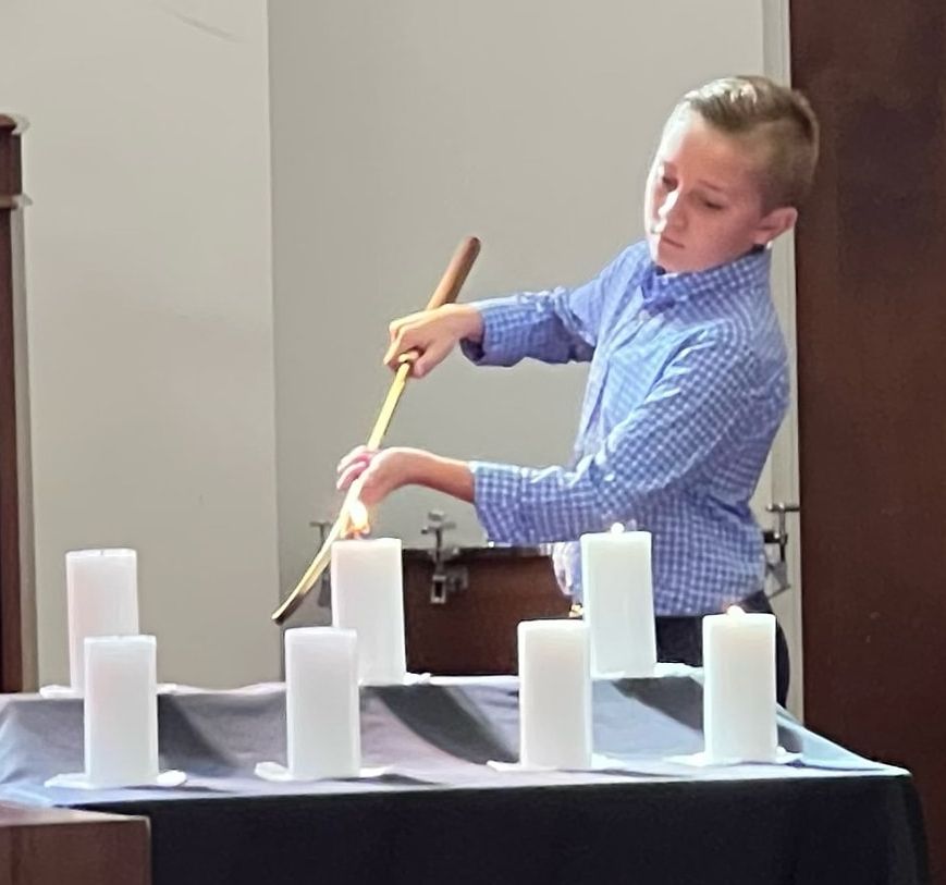 A young boy is lighting candles on a table
