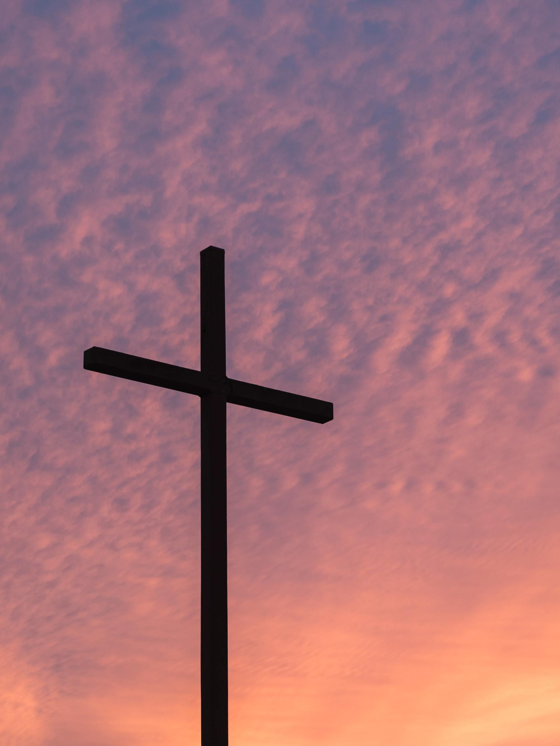 A cross is silhouetted against a sunset sky.