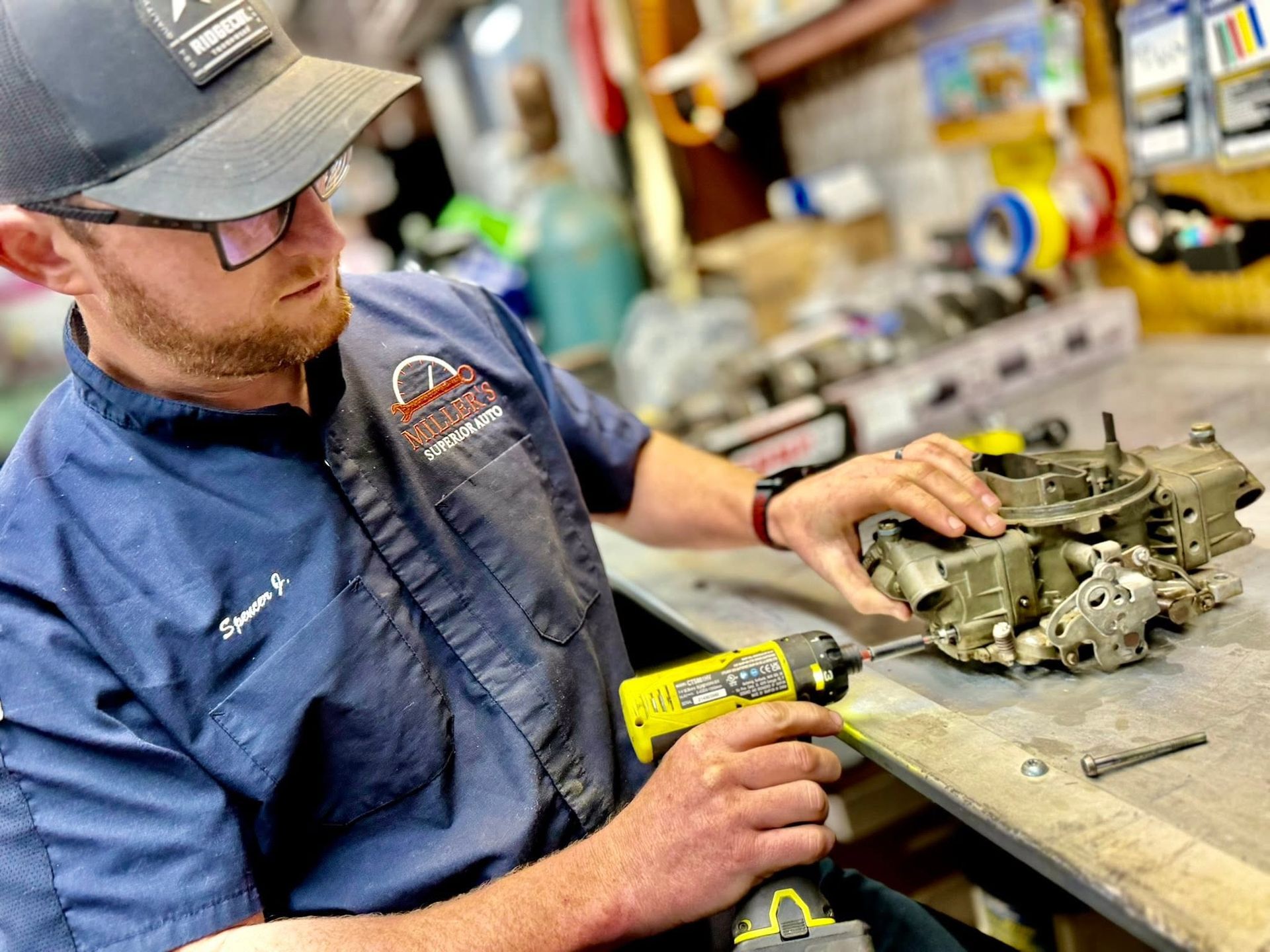 Mechanic using a yellow power tool on an engine on a workshop bench