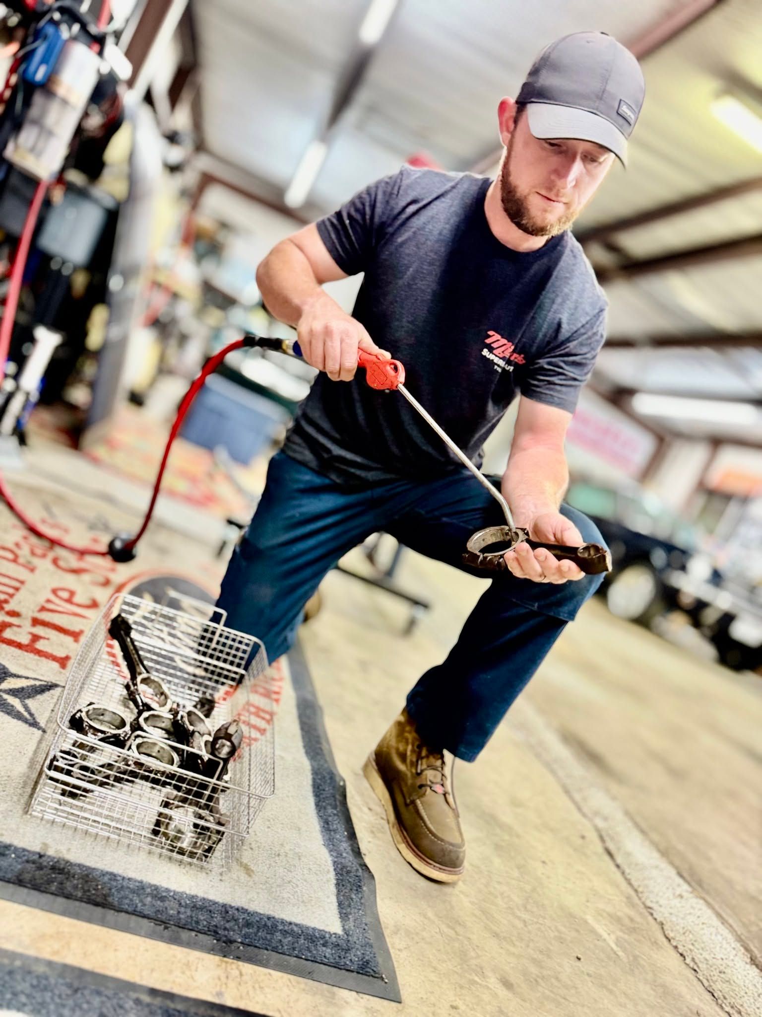 Worker using a cleaning wand to spray water into a floor drain in an industrial setting