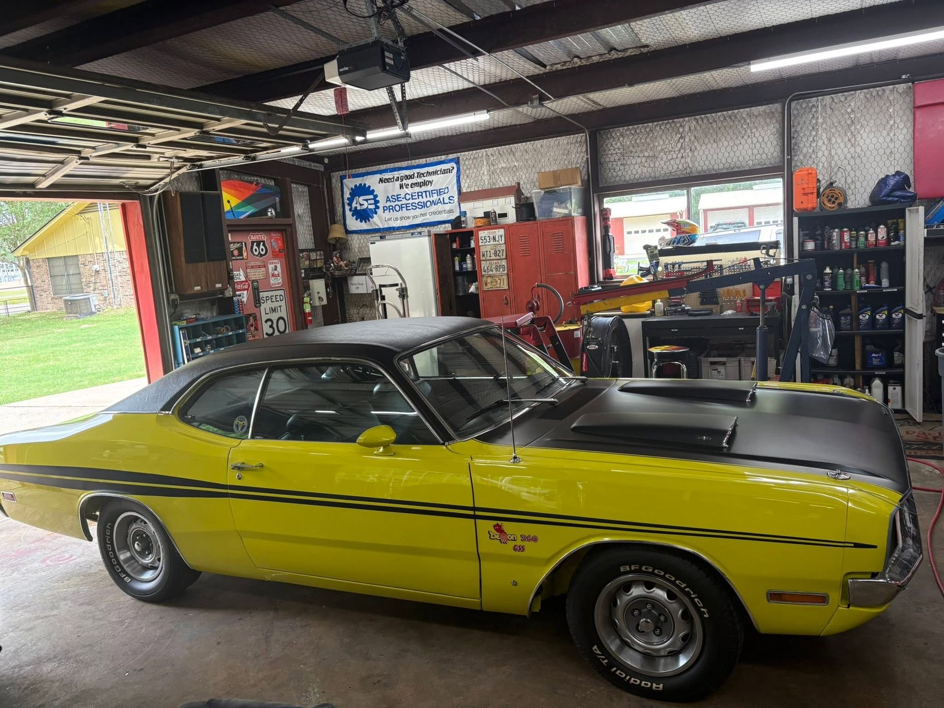 Yellow classic car parked inside a garage with tools and shelves in the background