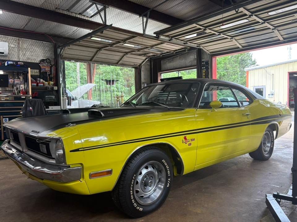 Yellow classic muscle car parked in a garage with its hood open