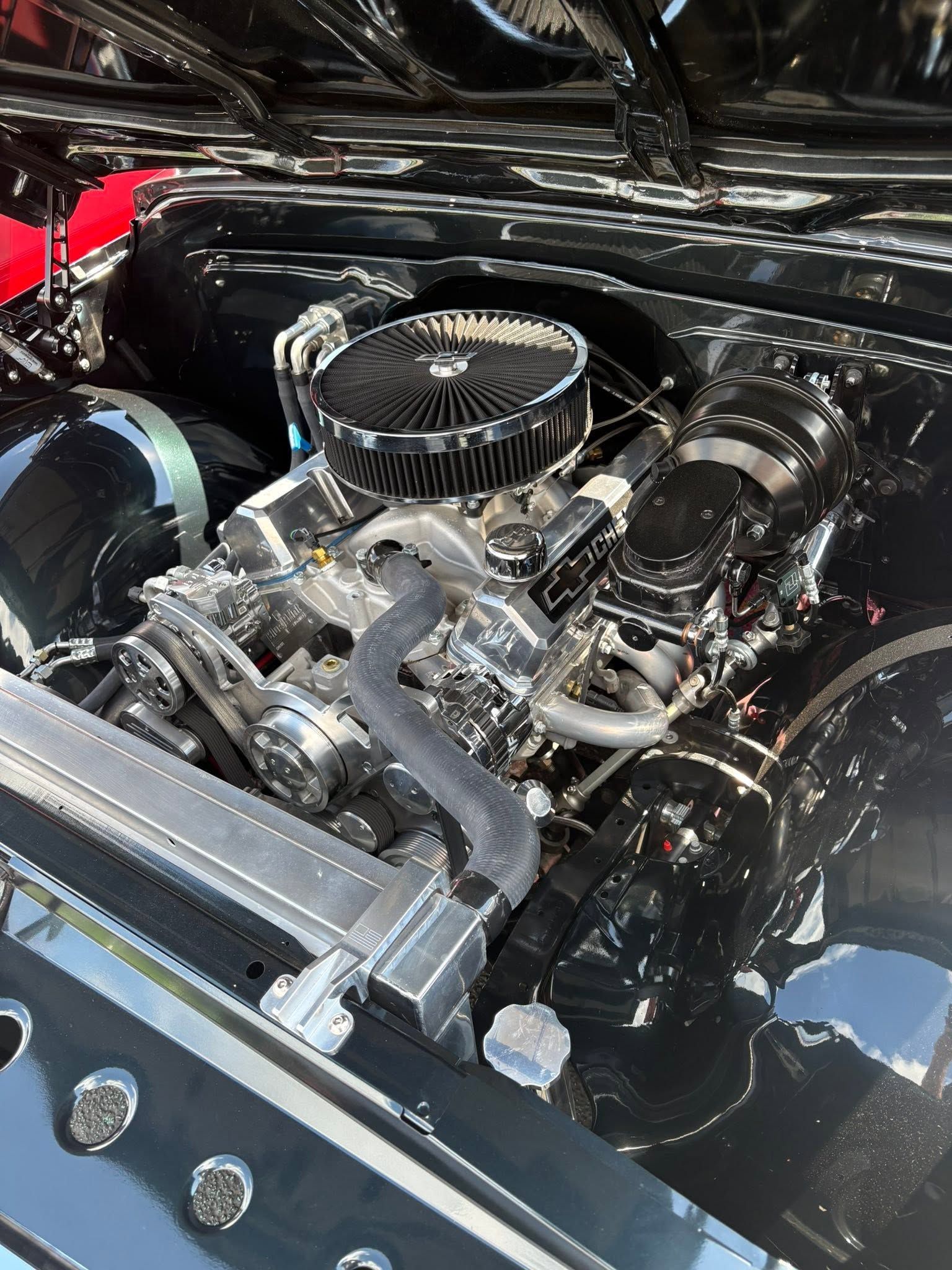Close-up of a polished car engine with a chrome air filter and black components under the hood