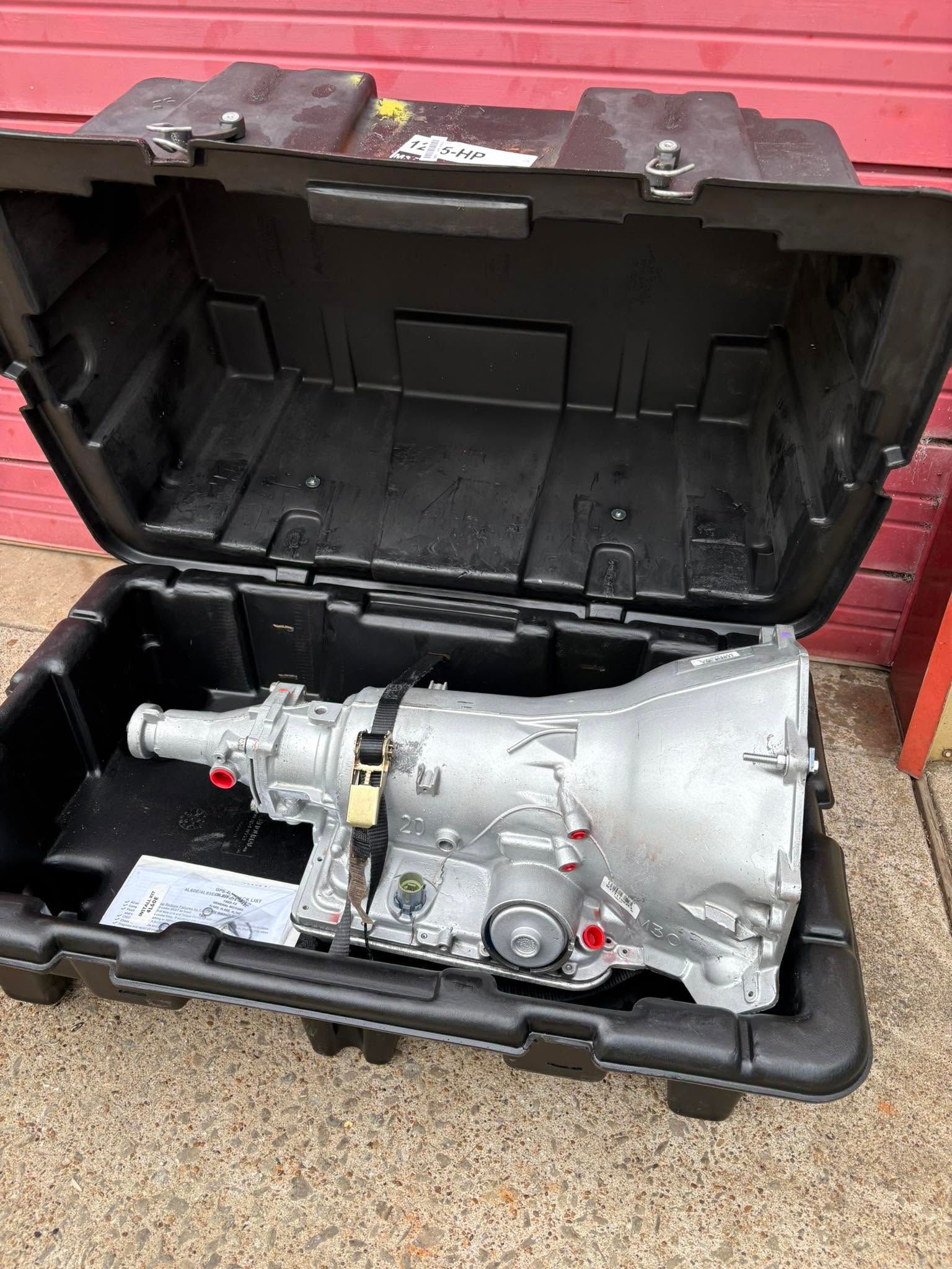 Silver transmission in open black hard case on red floor outdoors