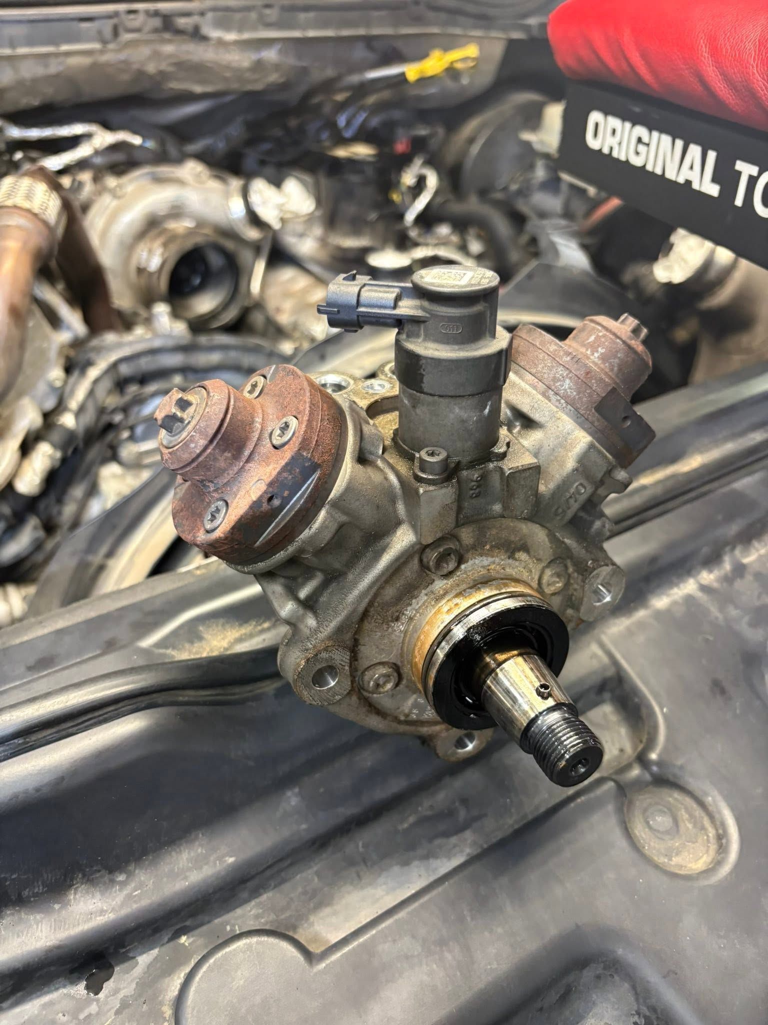 Close-up of a worn metal engine pump or fuel injector assembly on a car engine