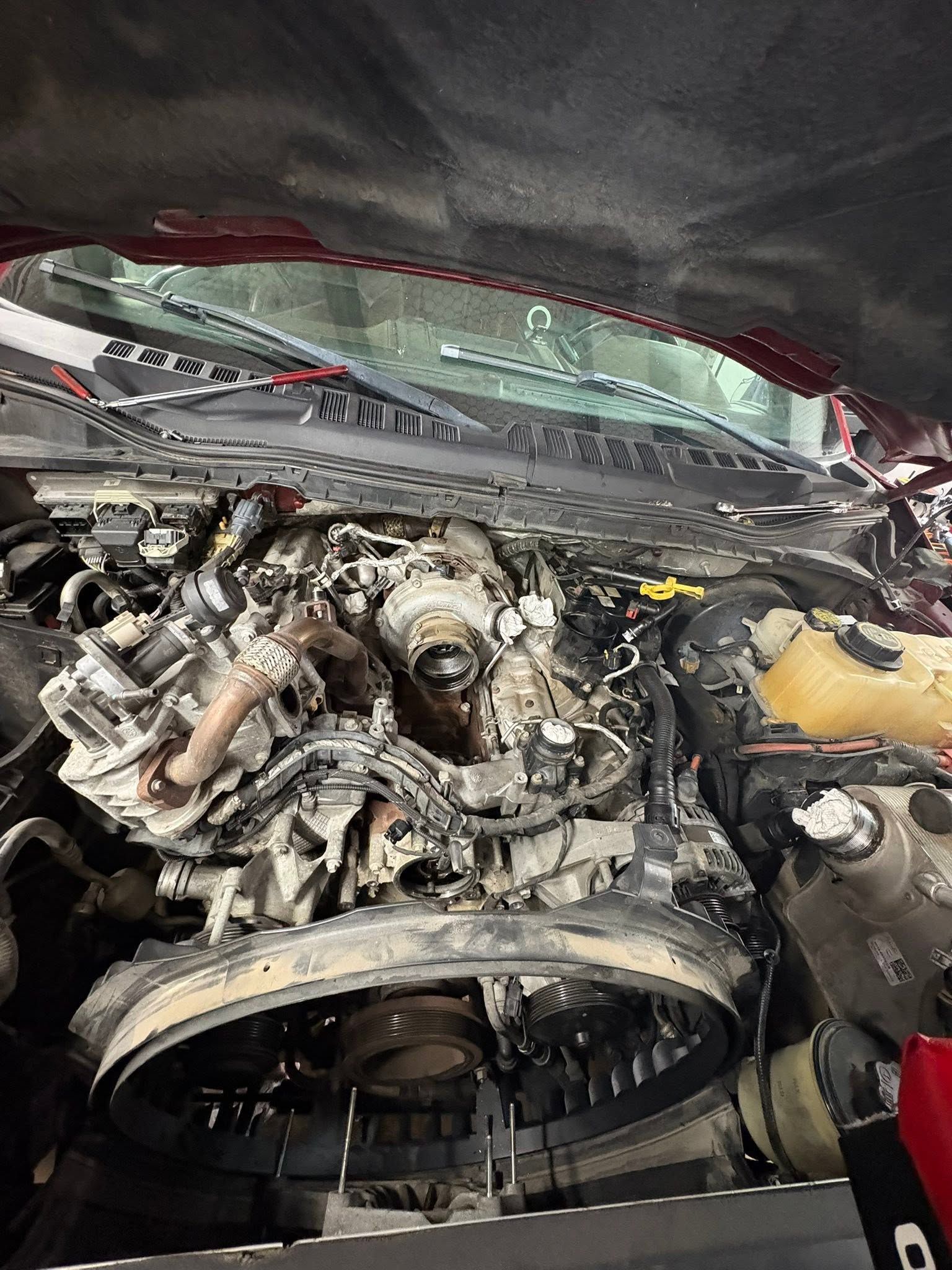 Damaged car engine compartment with exposed components and debris under the hood