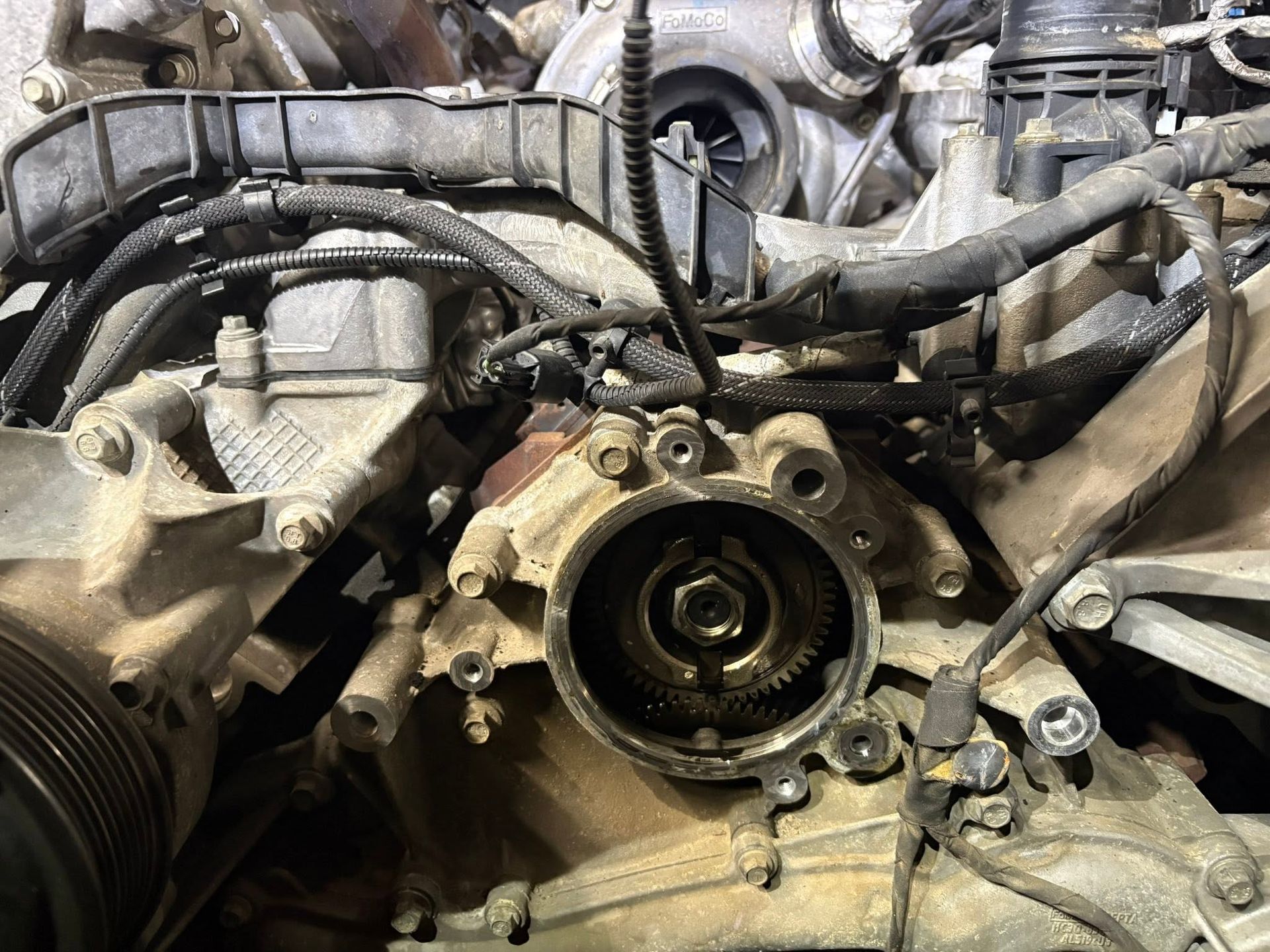 Close-up of a dirty car engine with the timing area exposed and parts removed