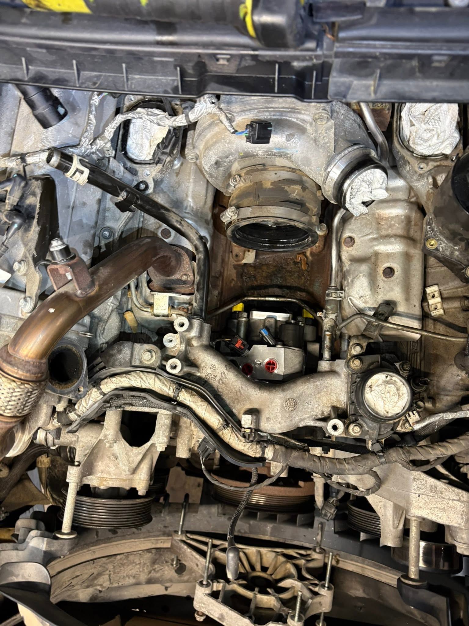 Close-up of a car engine bay with the engine removed, exposing hoses, metal components, and the transmission area.