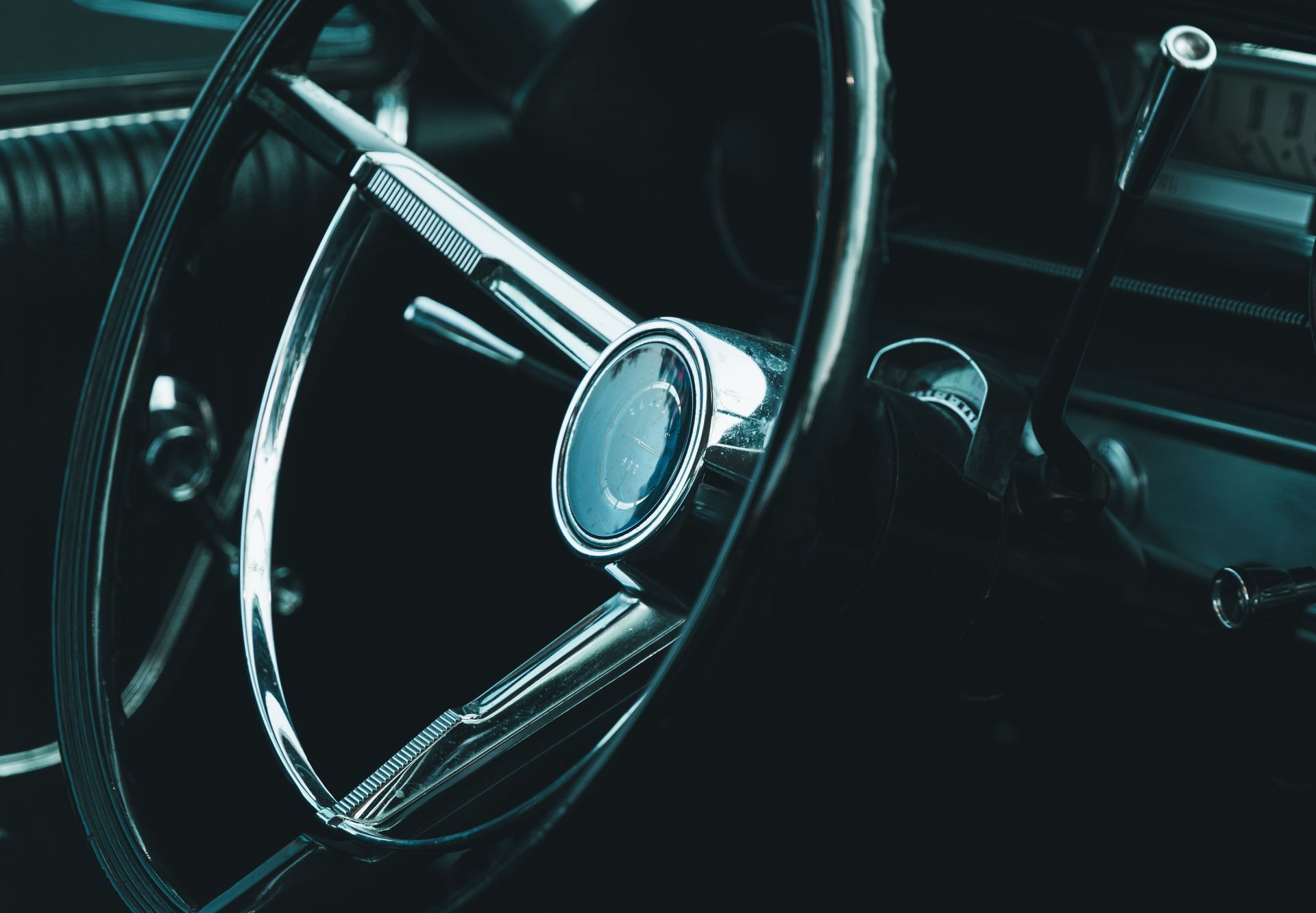 Close-up of a vintage car steering wheel and dashboard in dim light
