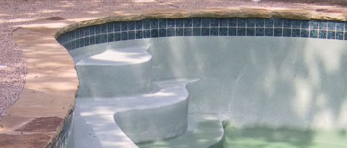 A swimming pool that has been emptied showing the stairs.