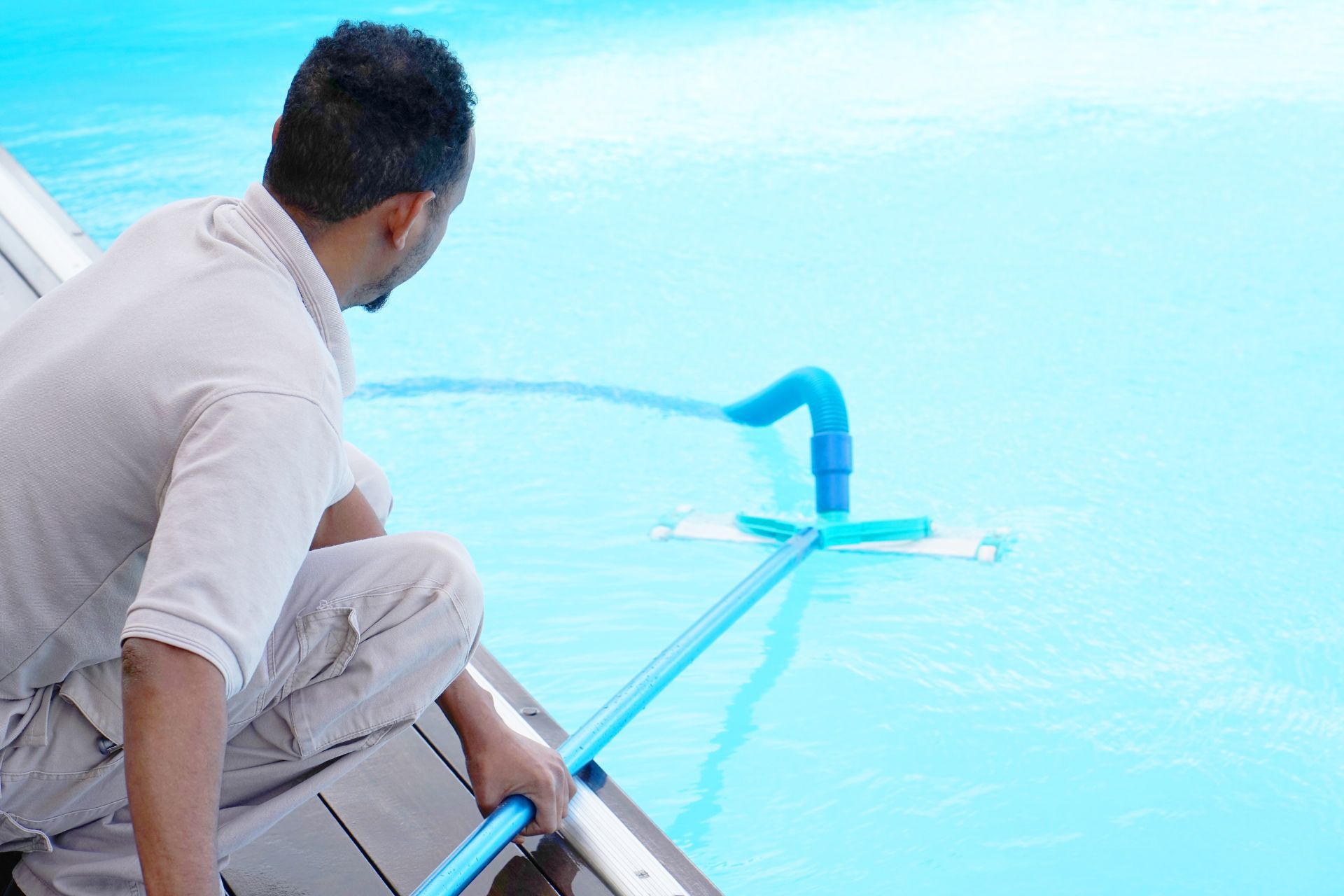 a man using a pool vacuum.