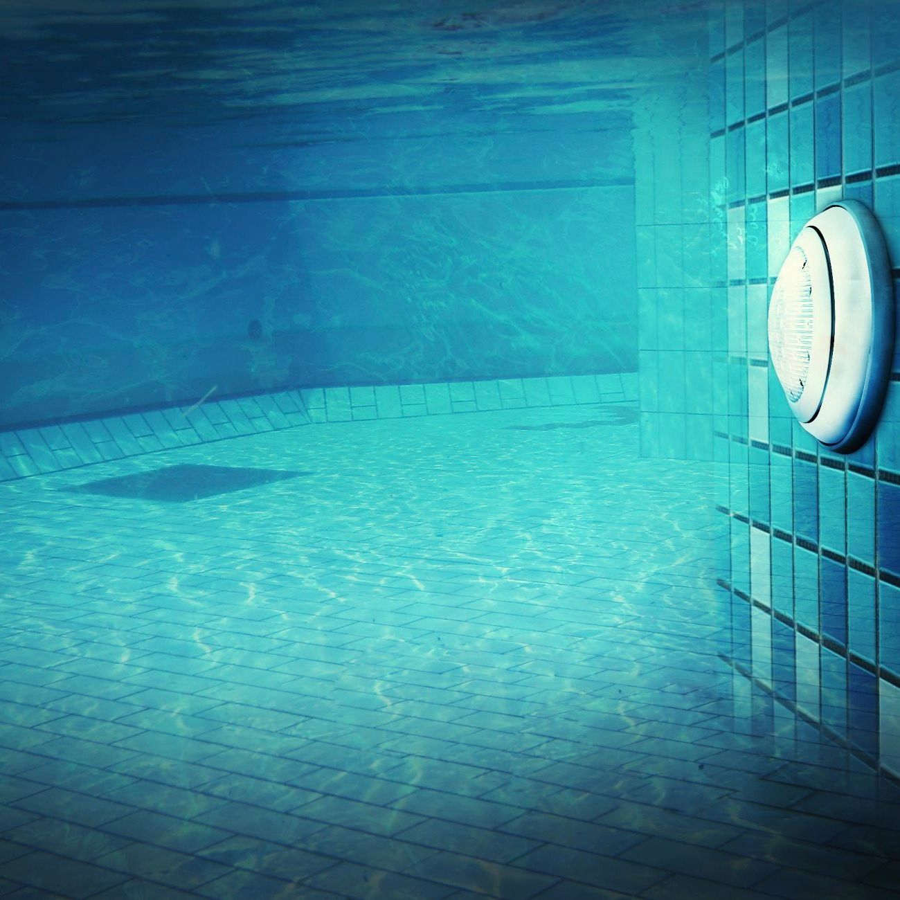 underwater of a swimming pool with the pool light in the foreground.