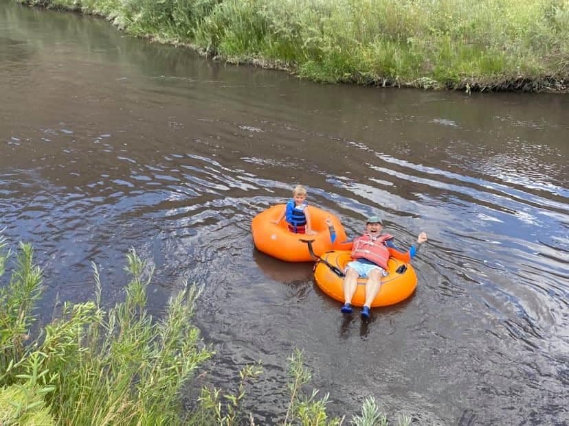 two people are floating down a river in orange tubes .