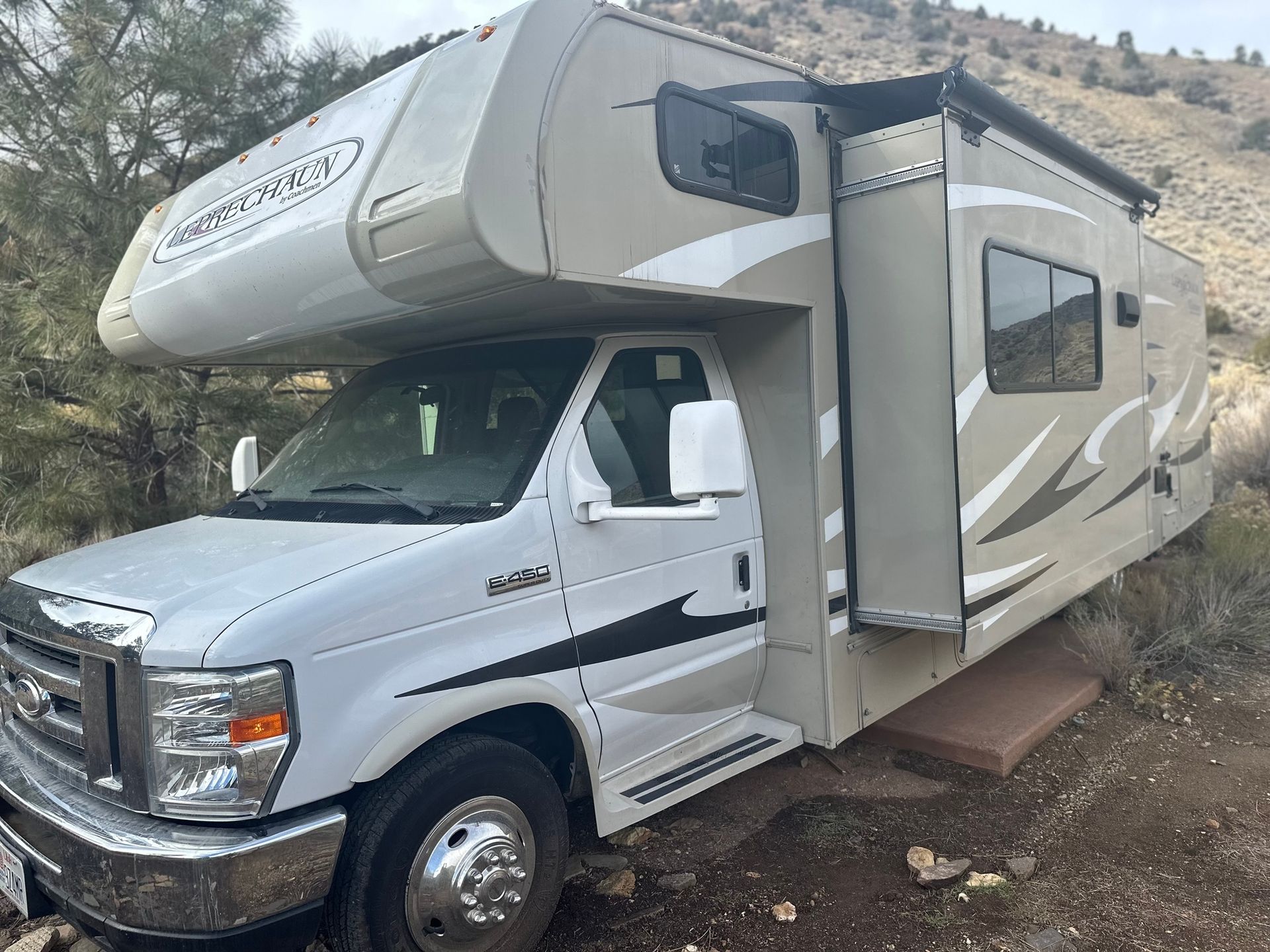 A white rv is parked on the side of a dirt road.