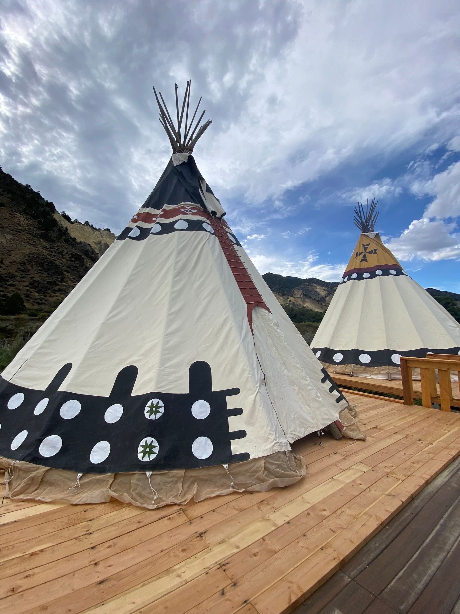 Two teepees are sitting on top of a wooden deck.