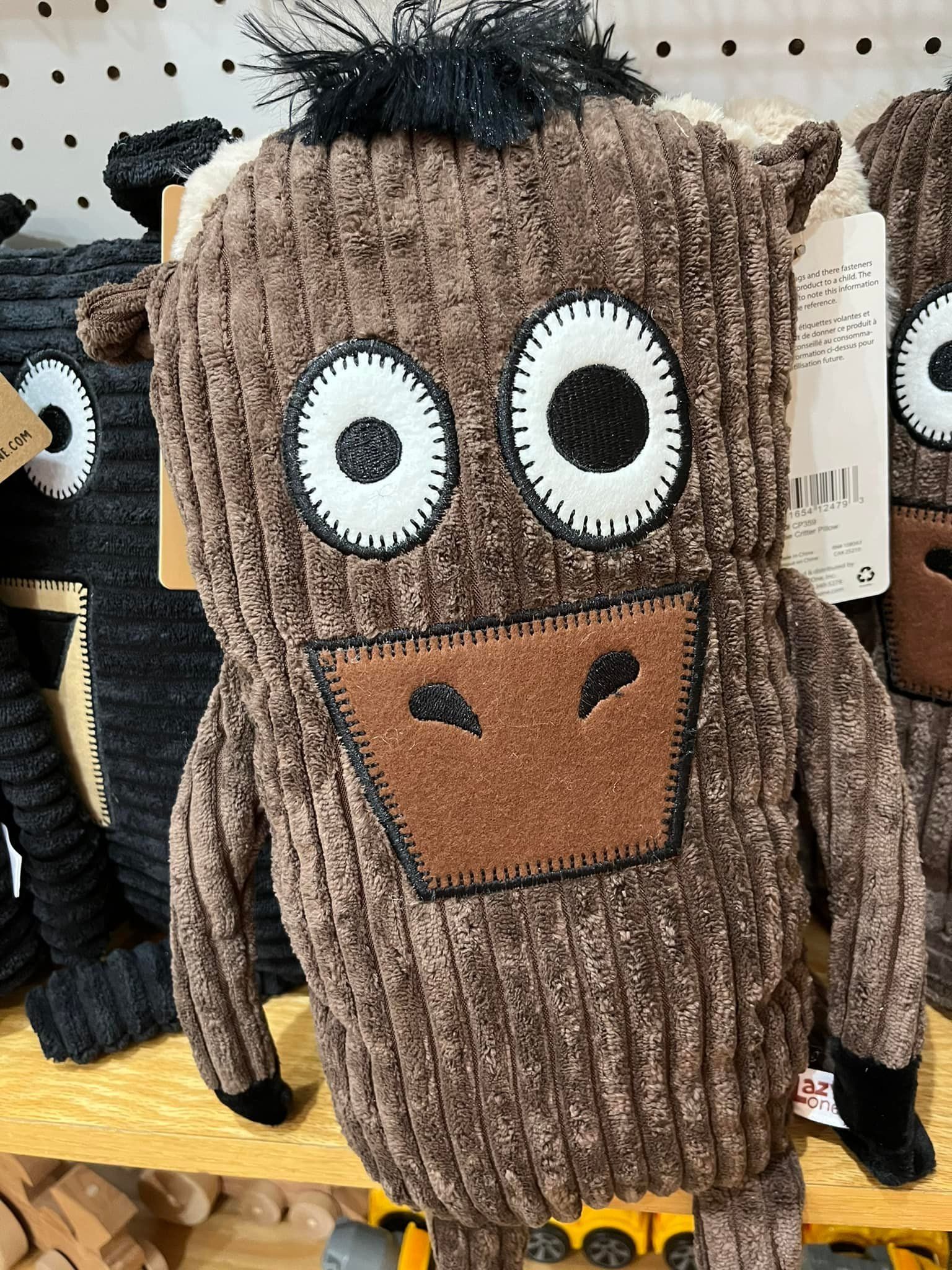 A stuffed animal with big eyes is sitting on a shelf.