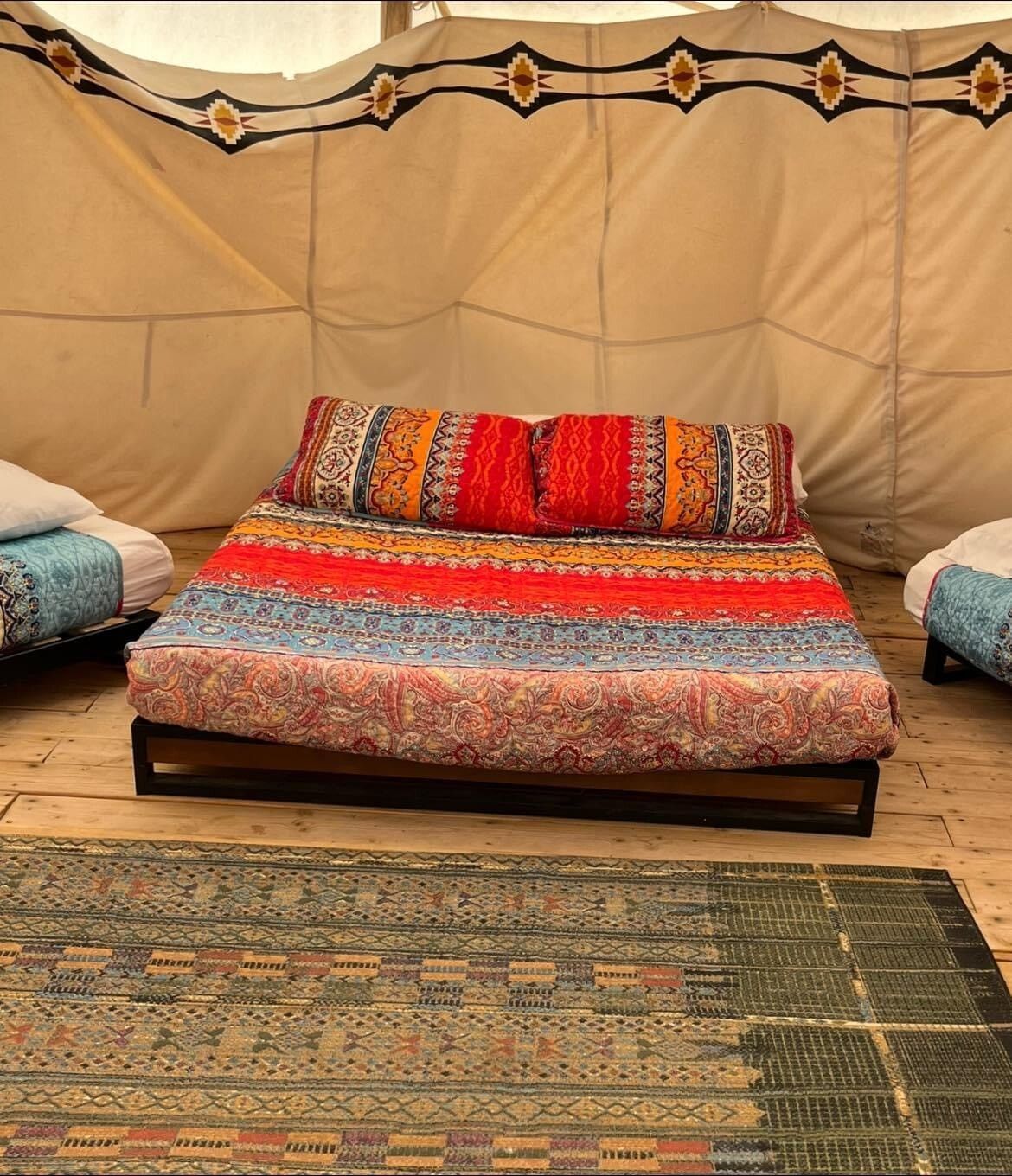 A bed in a tent with a rug on the floor