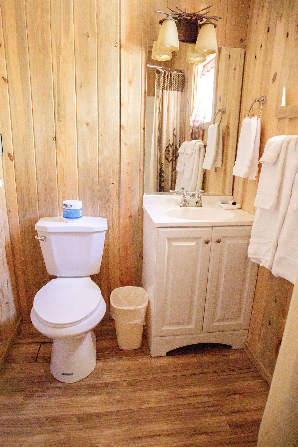 A bathroom with a toilet , sink and mirror.