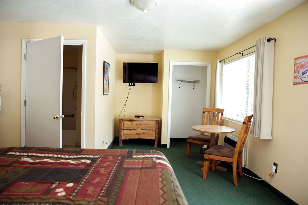 A hotel room with a table and chairs and a flat screen tv