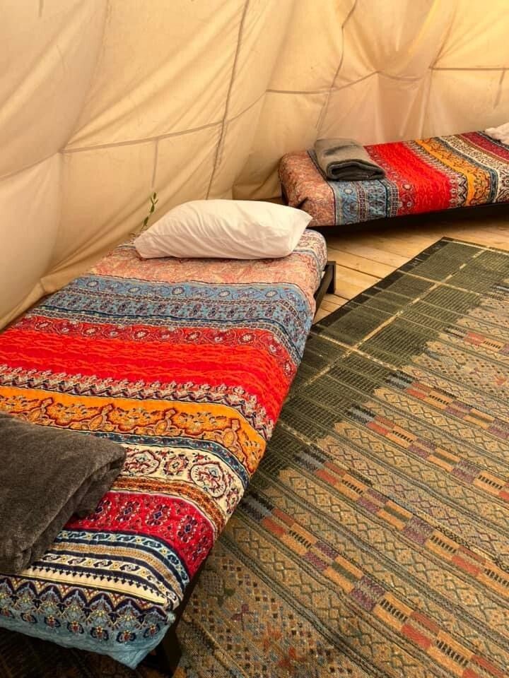 A tent with two beds and a rug in it.