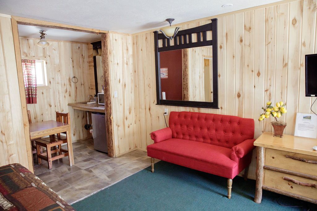 A living room with a red couch and a mirror