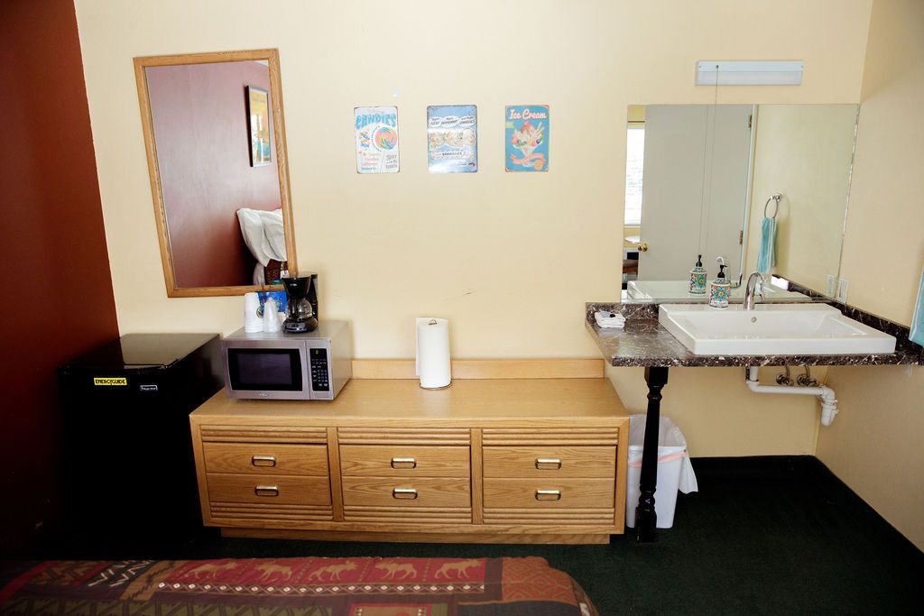 A hotel room with a microwave a sink and a mirror